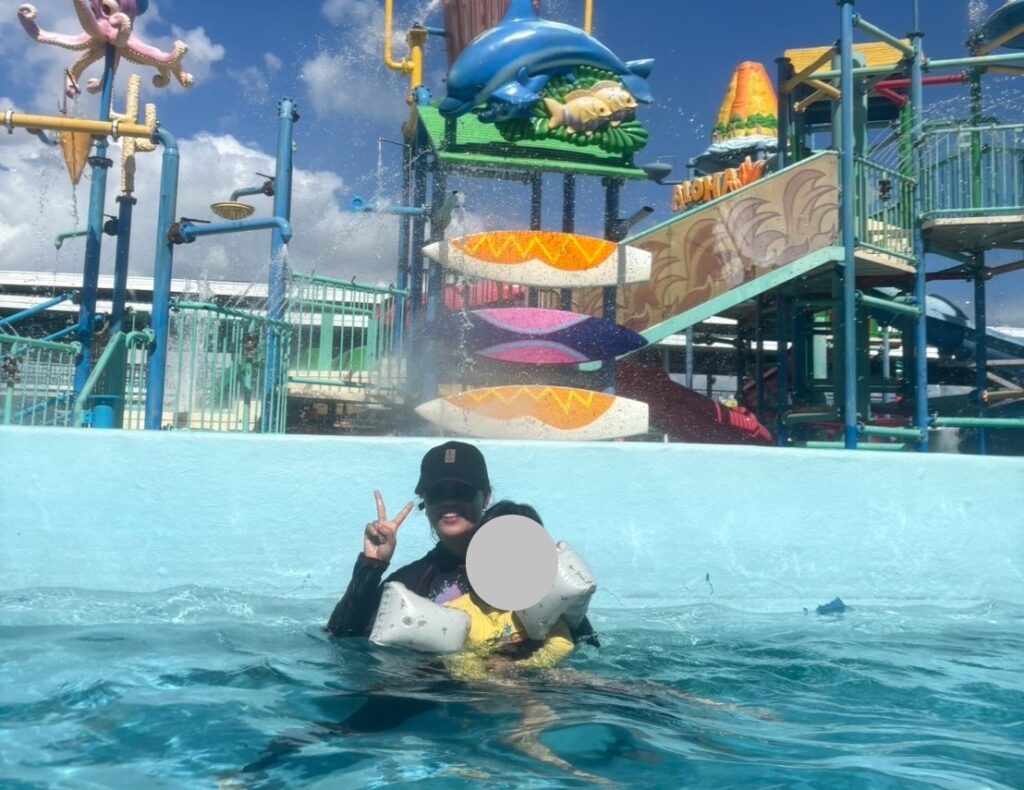 プールでラッシュガードをきた女性と子供が遊んでいる写真